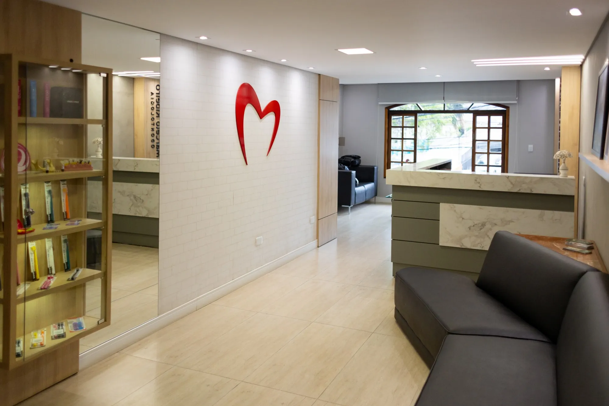 Sala de espera da clínica Marcelo Ribeiro Odontologia, com o símbolo da marca na parede