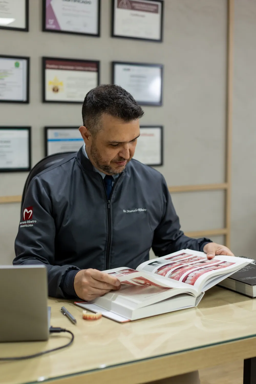 Dr. Marcelo Ribeiro lendo um livro de odontologia no consultório