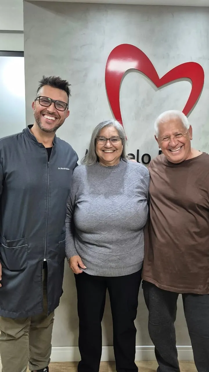 Casal de pacientes sorrindo ao lado do Dr. Marcelo Ribeiro